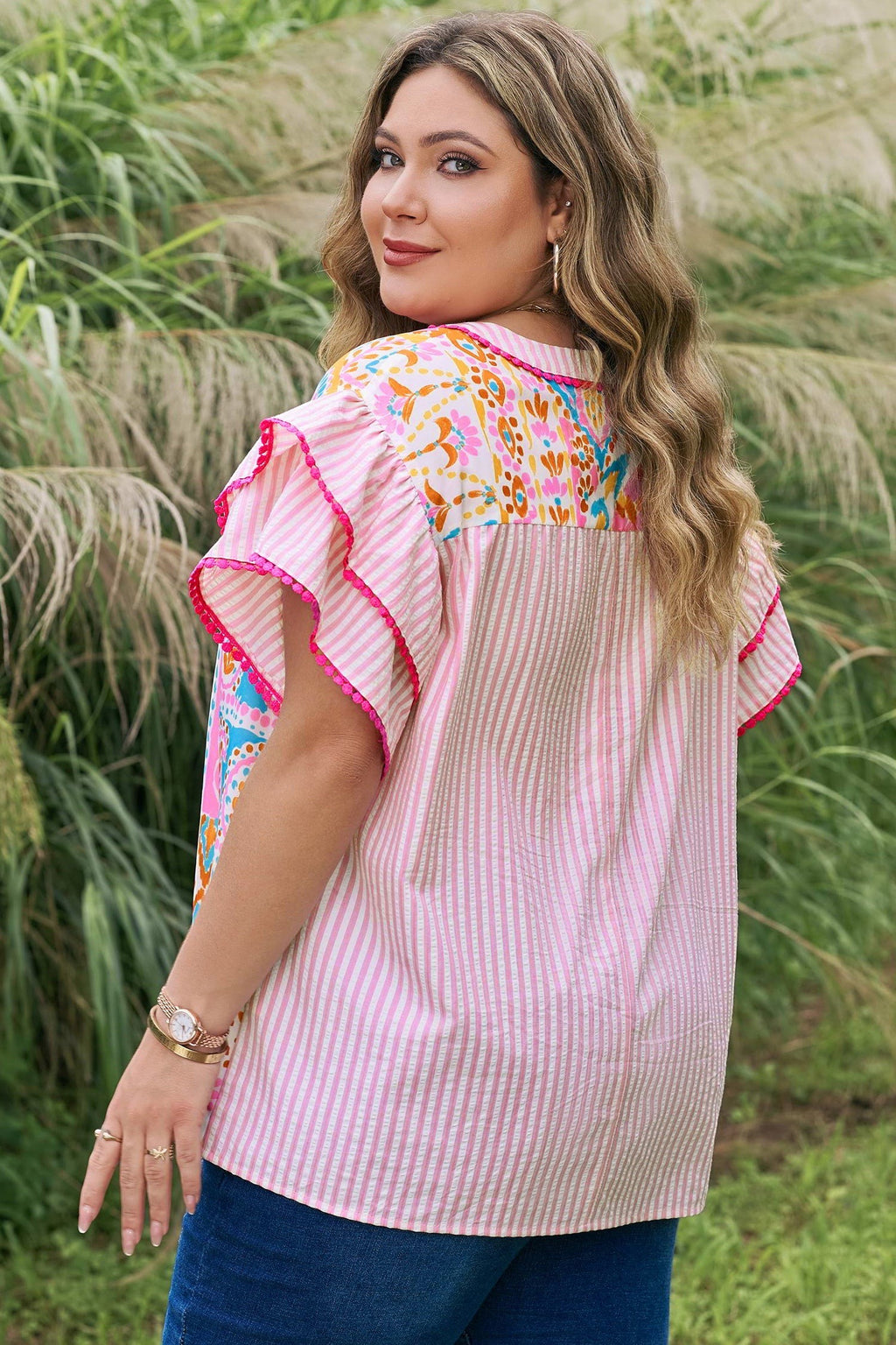 Somethinguluv plus size blouse with pink stripes, floral print, and ruffled flutter sleeves in a garden setting