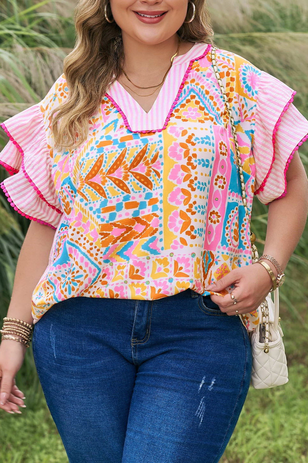 Somethinguluv plus size blouse with a vibrant geometric print, V-neck, and ruffled flutter sleeves in pink and orange.