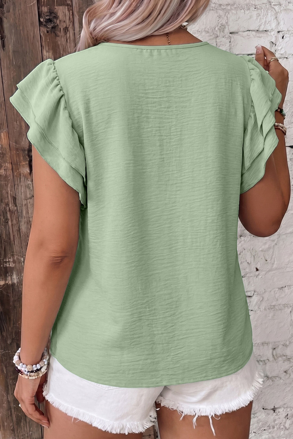 Back view of a Somethinguluv sage green plus size blouse with layered flutter sleeves and a round neckline.