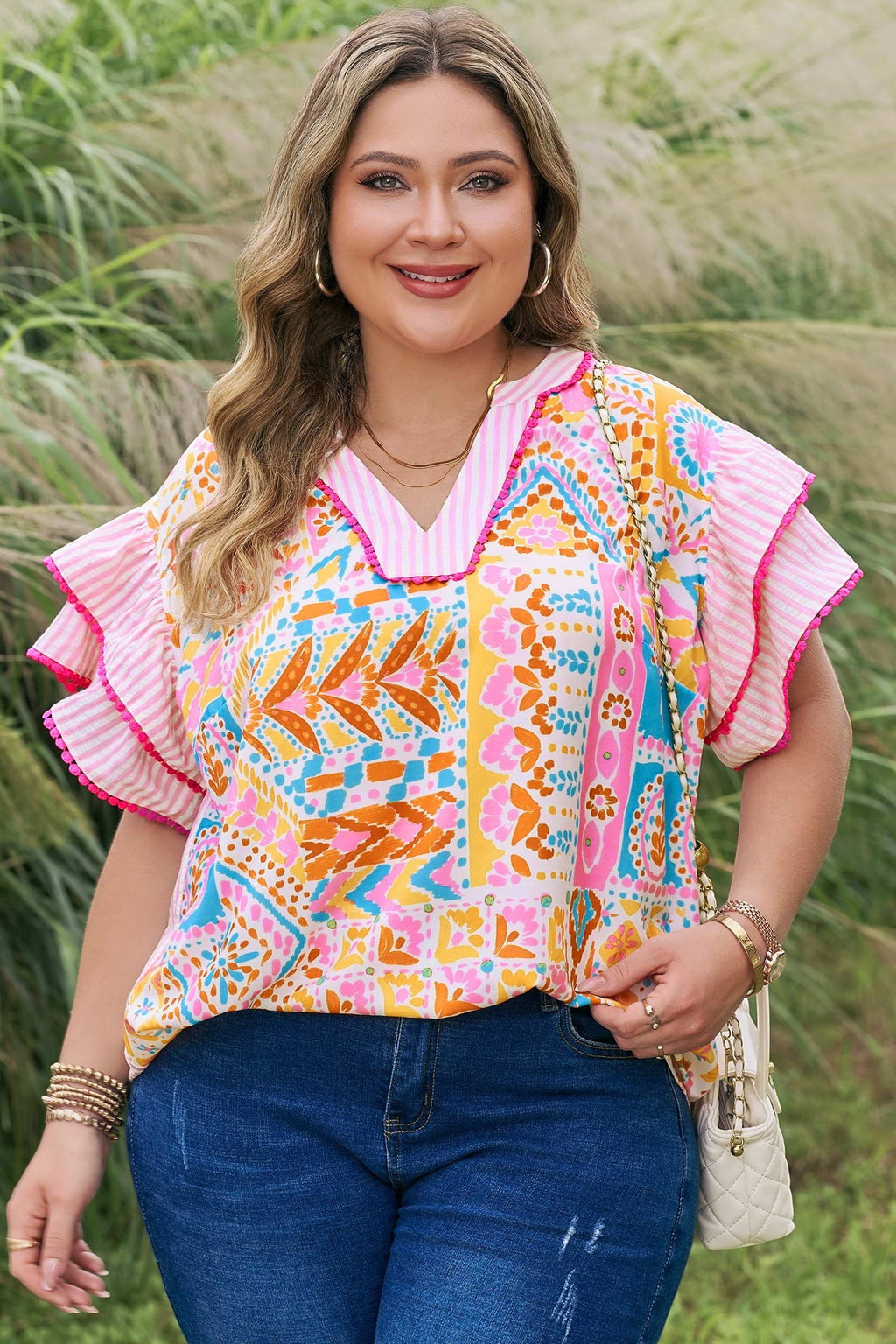 Somethinguluv3 plus size blouse with vibrant geometric print, V-neck, and pink-trimmed flutter sleeves.