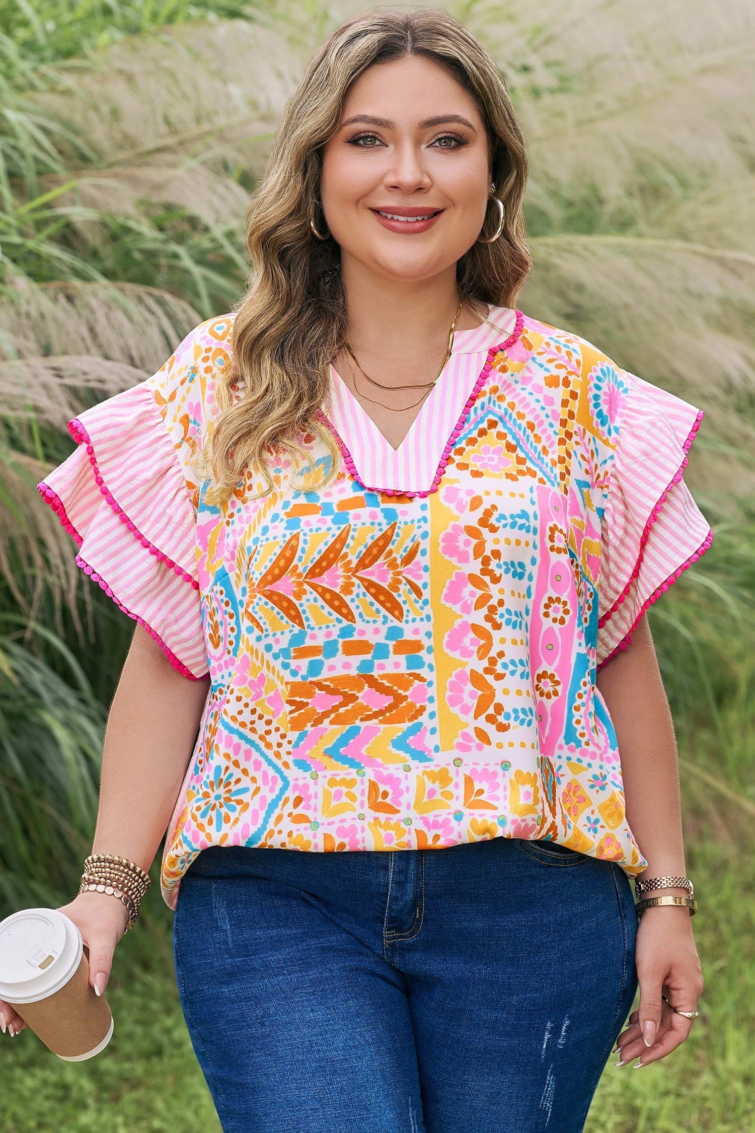 Somethinguluv3 plus size blouse with a vibrant geometric print, V-neck, and pink ruffled flutter sleeves.