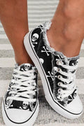 Somethinguluv3 black canvas low top sneakers featuring a white skull and crossbones print and frayed edge detailing.