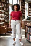 Somethinguluv3 white distressed cropped denim pants worn by a woman with a red t-shirt and white sneakers in a library